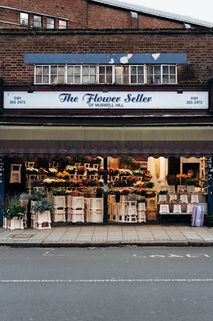 The storefront of The Flower Seller, a florist shop on Muswell Hill, displaying a wide variety of fresh flowers arranged in bouquets and floral displays. The display windows are filled with colorful b